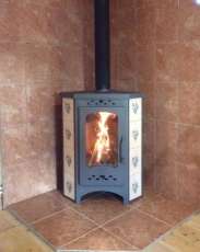 Недорогая печь-камин Бавария угловая с плитой незабудка Амазонка бай фото в интерьере в Мозыре